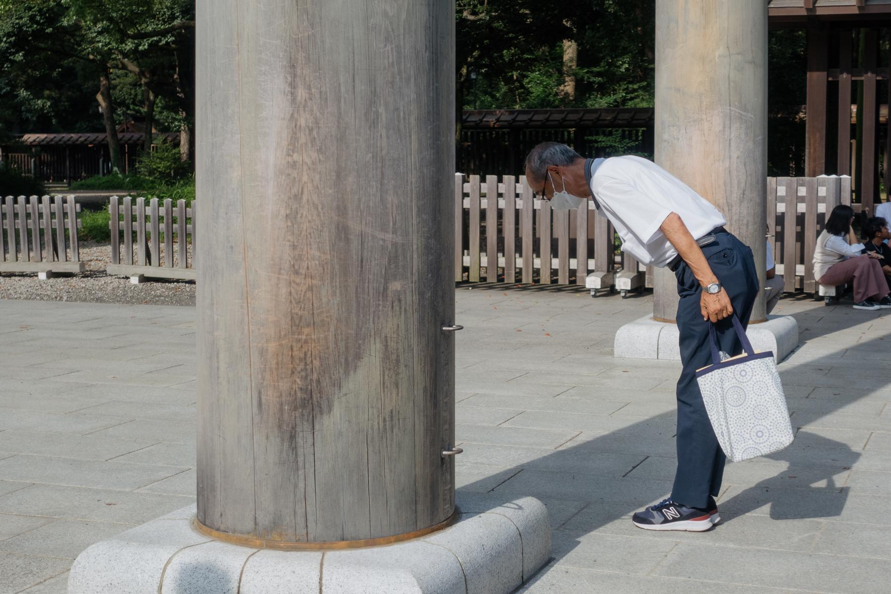 A visitor at Meiji shrine in Tokyo bows before passing through the <i>torii</i> gate. A <i>torii</i> is seen as an entryway into sacred space.